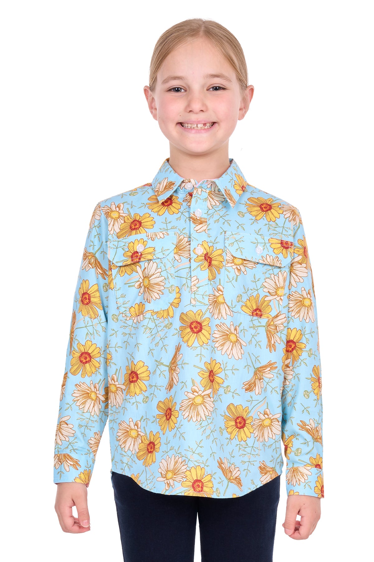 A young girl with blonde hair tied back, wearing a light blue long-sleeve button-up shirt with a yellow and orange floral pattern, paired with dark pants, standing against a plain white background.