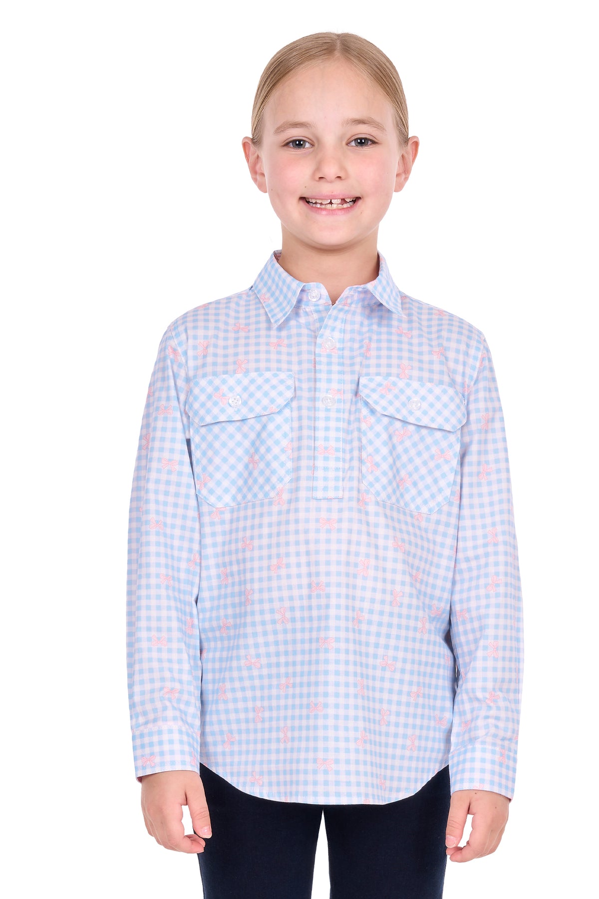 A young girl with blonde hair tied back, wearing a light blue and white gingham long-sleeve button-up shirt with a pink flamingo pattern, standing against a solid white background.