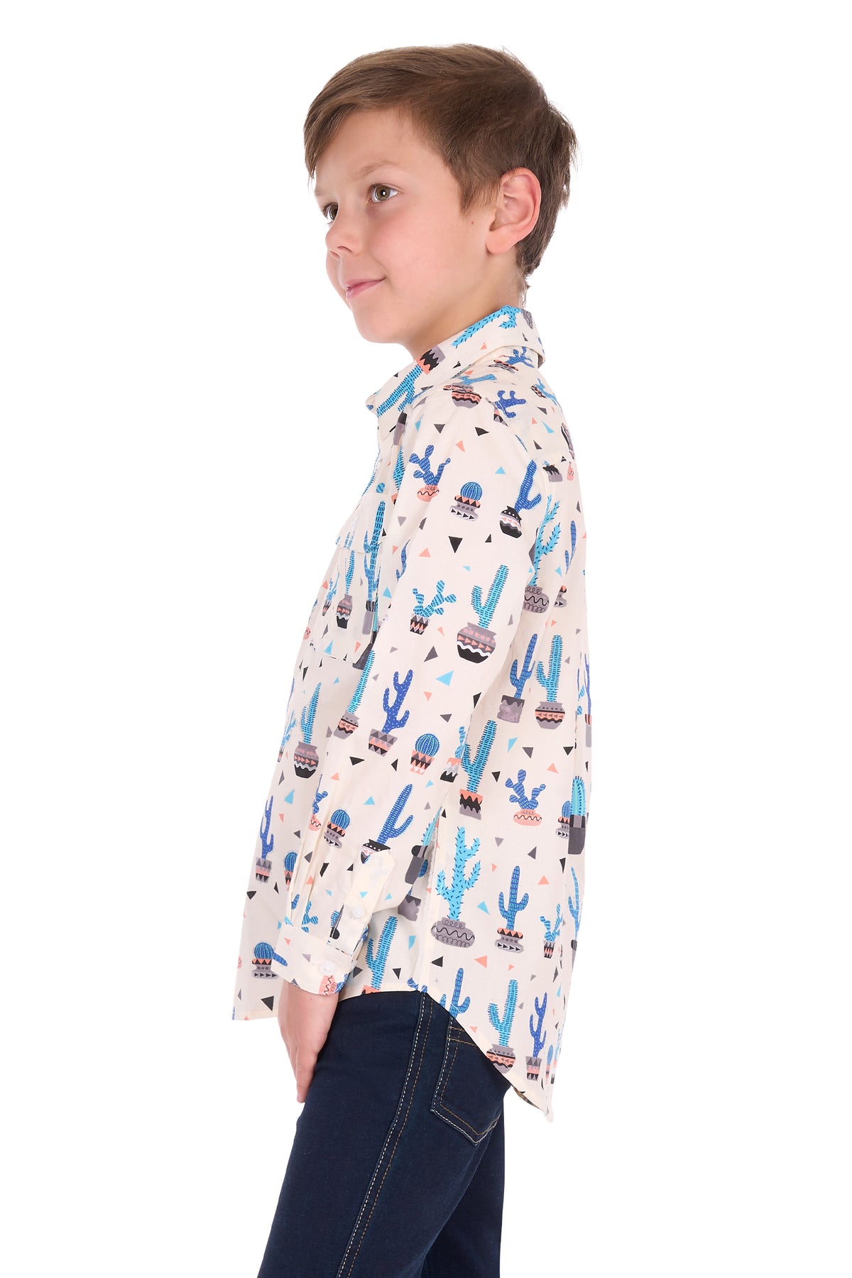 A young boy wearing a long-sleeve button-up shirt with a colorful desert cactus pattern, paired with dark blue jeans, shown in profile against a white background.