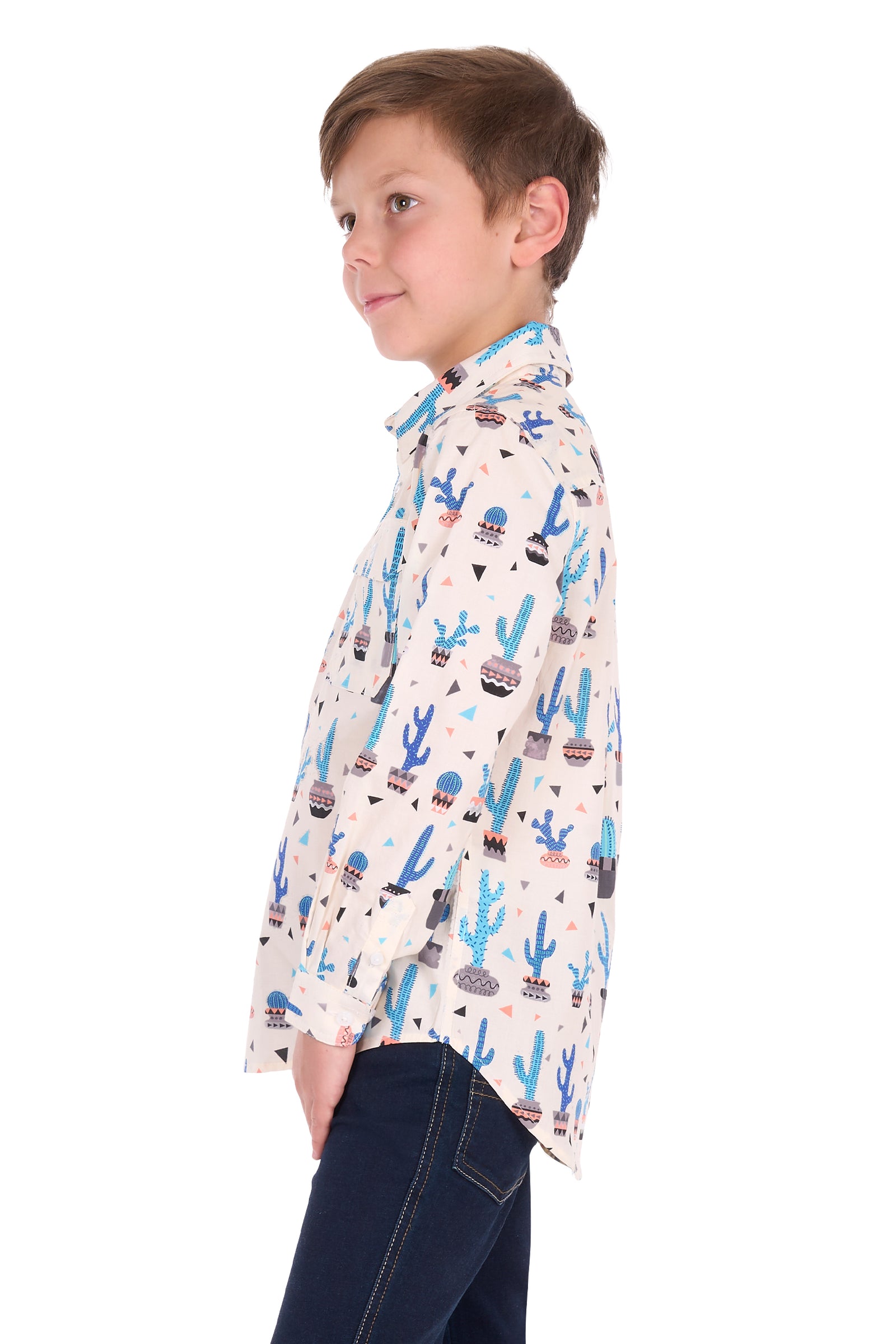 A young boy wearing a long-sleeve button-up shirt with a colorful desert cactus pattern, paired with dark blue jeans, shown in profile against a white background.