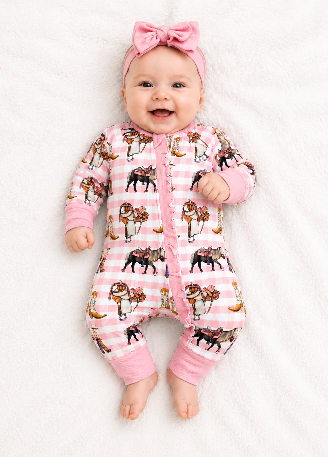 Baby wearing a pink pajama with horse print on a white background