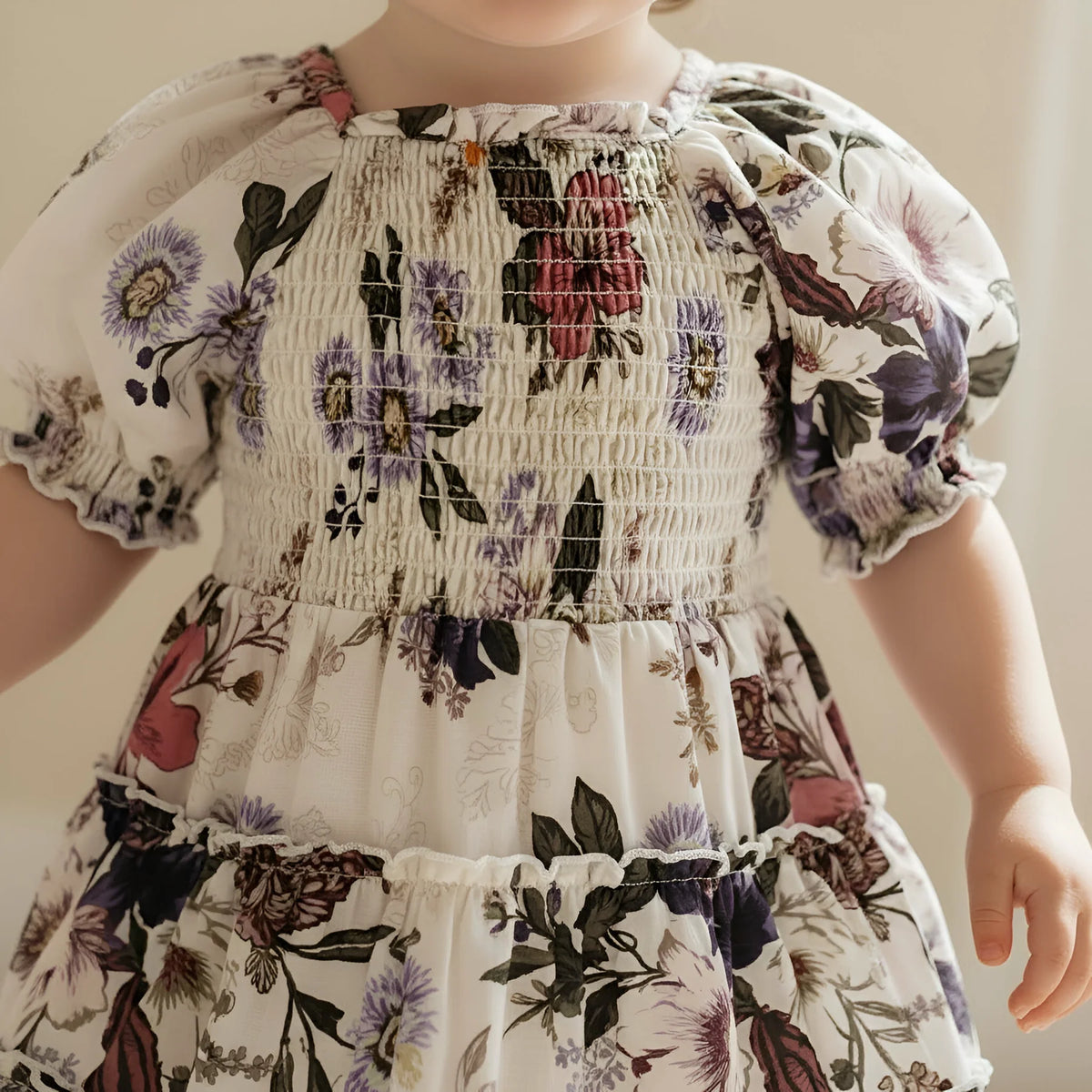 Child wearing a floral dress with a neutral background