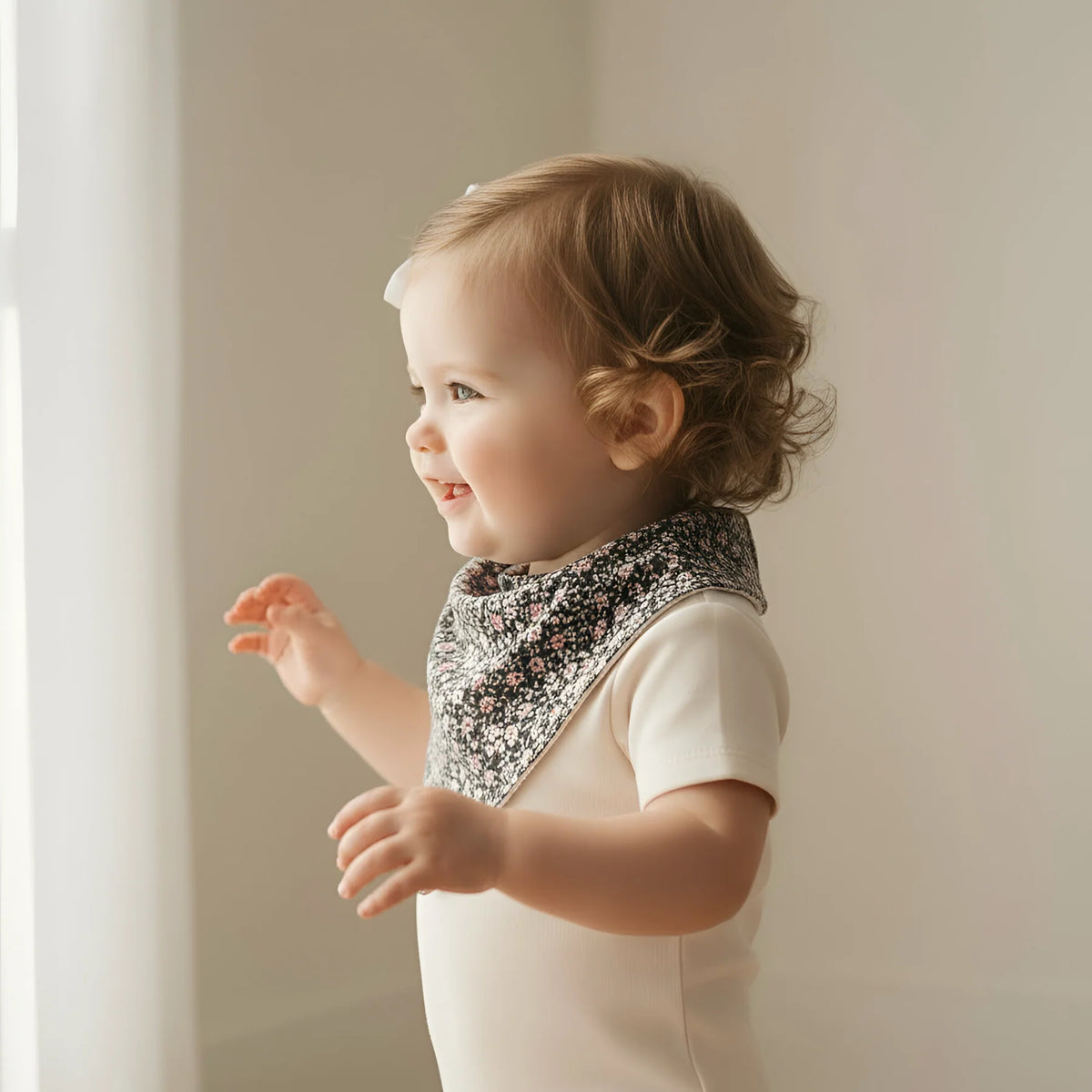 Baby wearing a floral bib against a neutral background