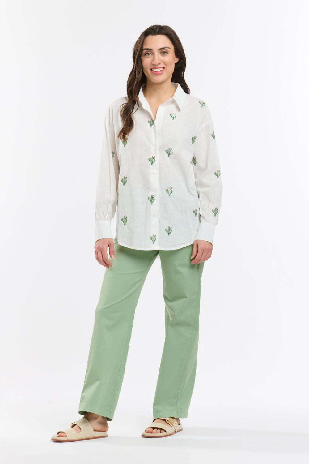 Italian Star Women's Cactus L/S Shirt. Woman wearing a white blouse with green patterns and green pants on a white background