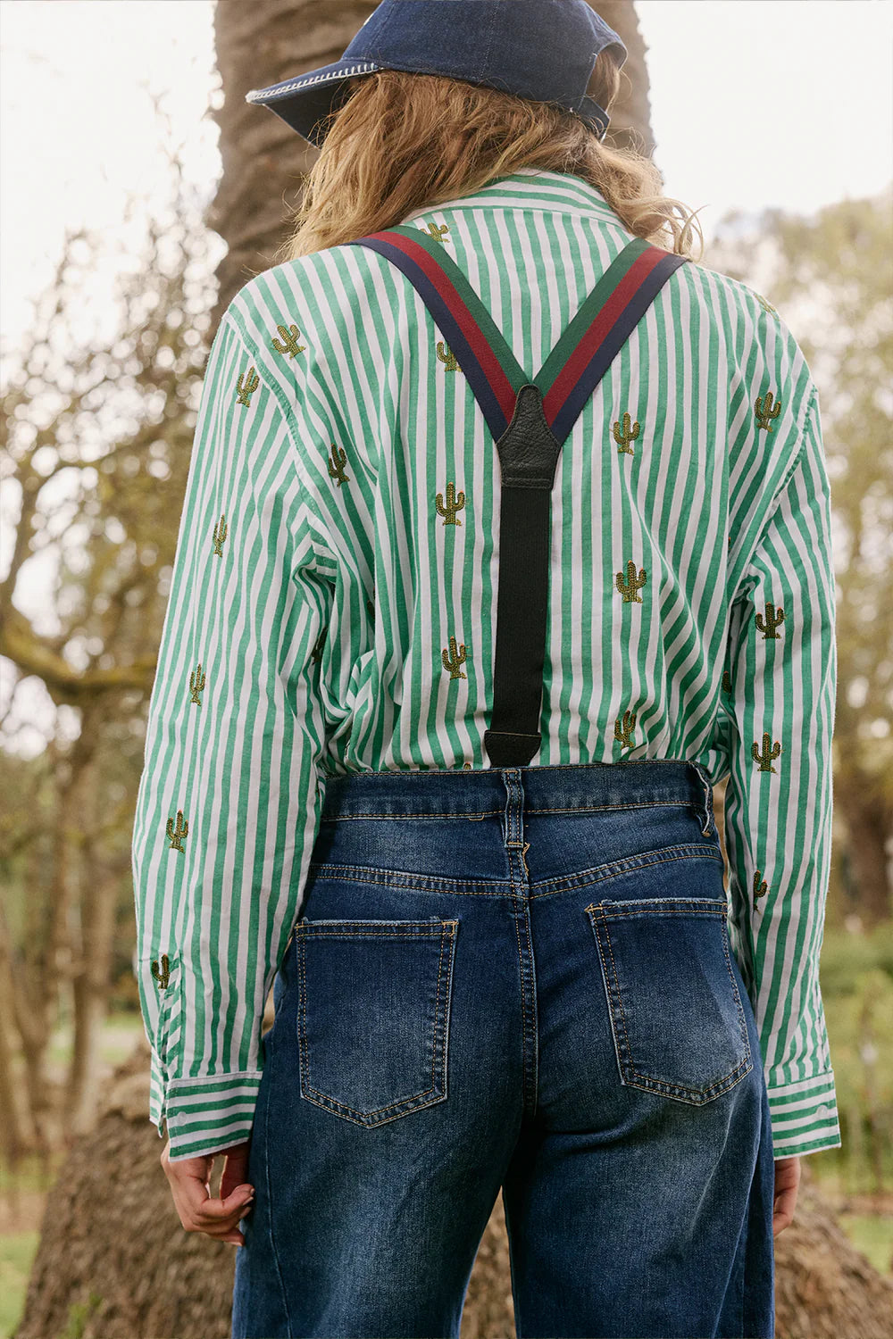 Italian Star Women's Stripe Cactus Shirt. Person wearing a green and white striped shirt with suspenders and blue jeans in a natural setting.