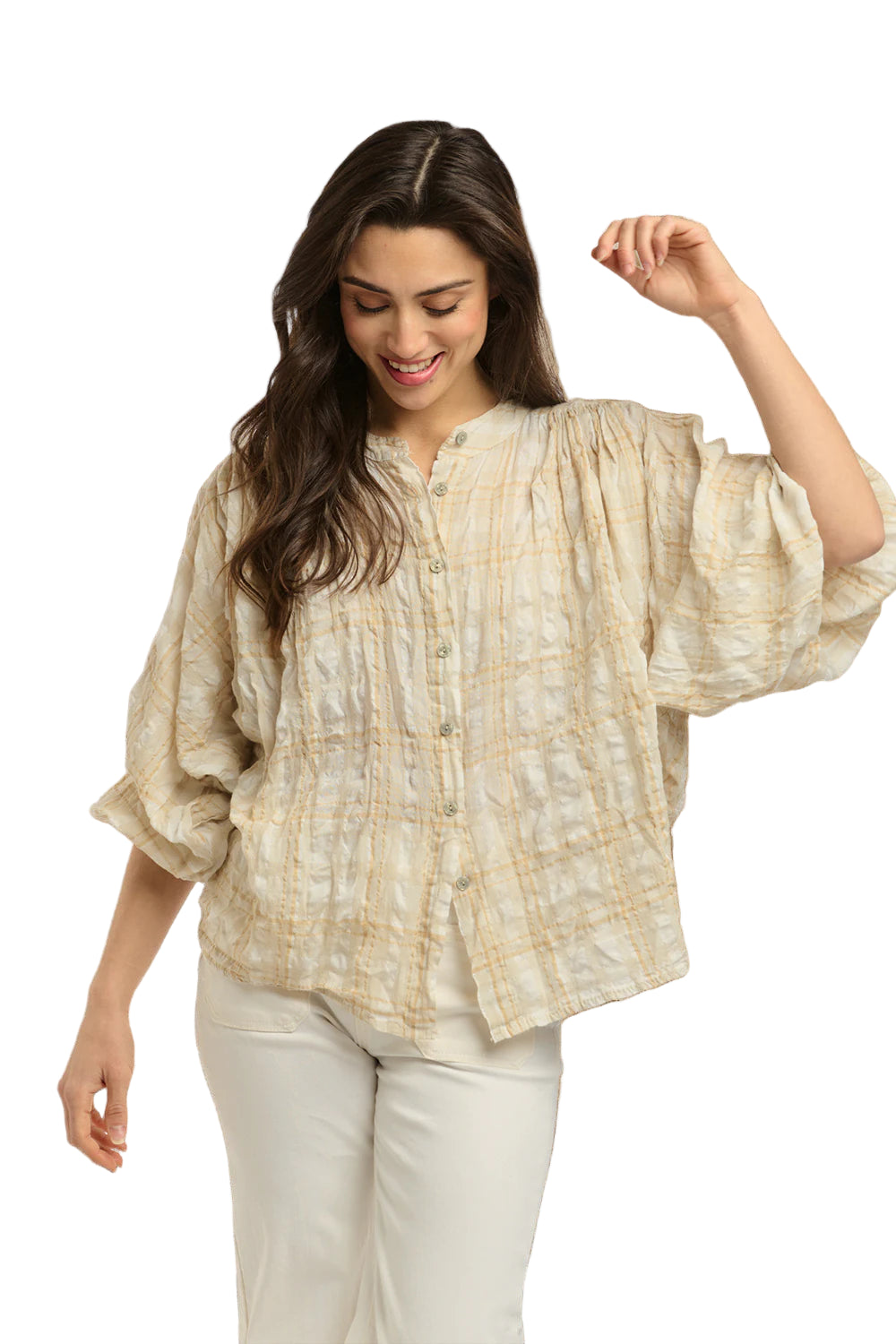 Italian Star Women's Freida Check Shirt. Woman wearing a light-colored blouse with a textured pattern against a stone wall.