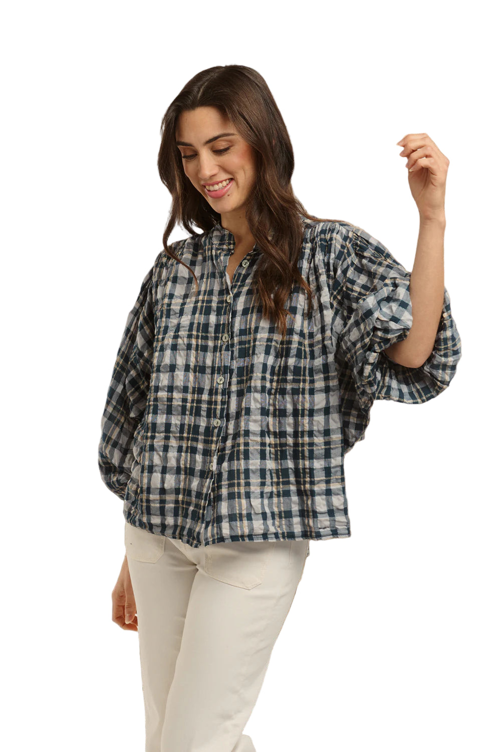 Italian Star Women's Freida Check Shirt. Woman wearing a blue plaid shirt and white pants standing against a stone wall.