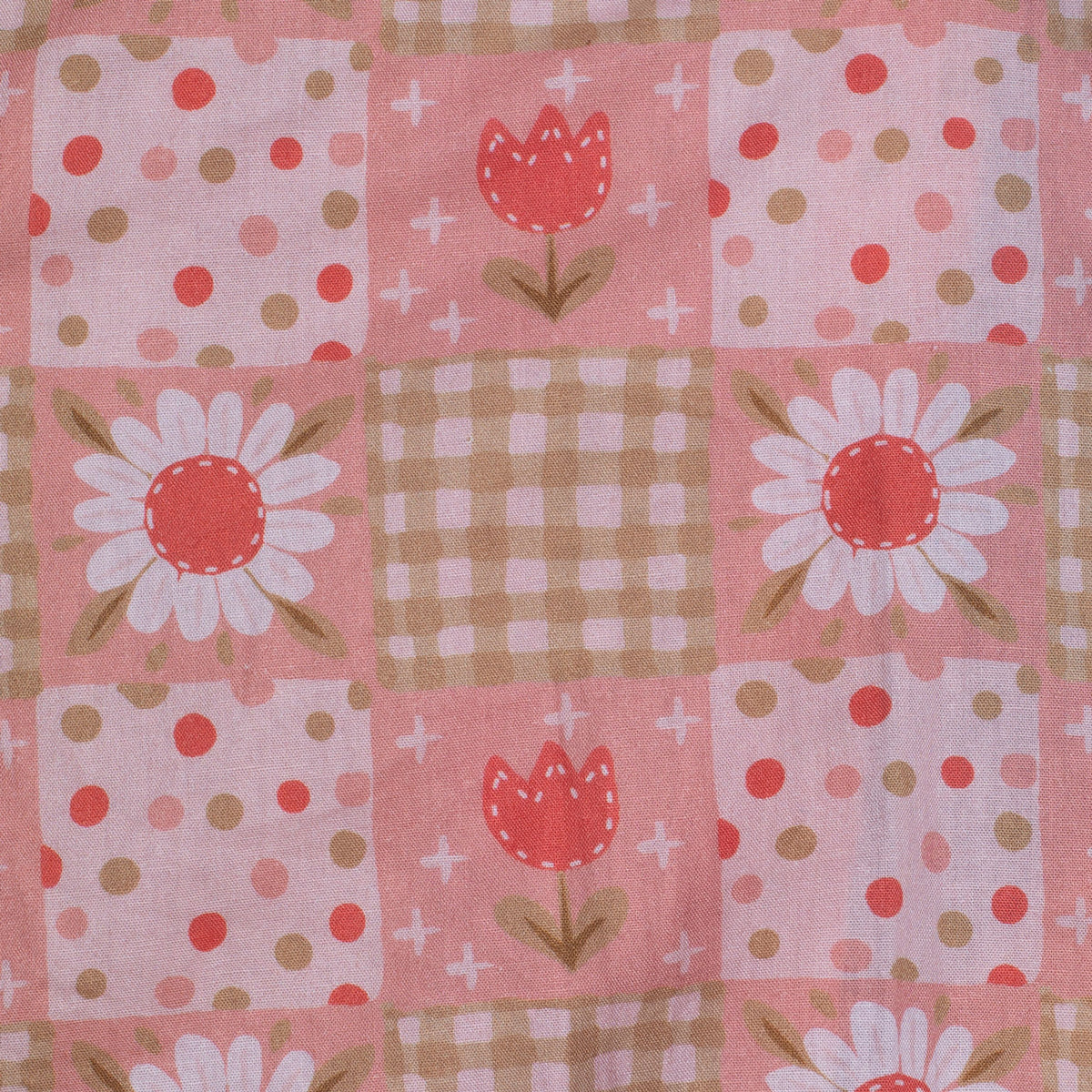 Patchwork fabric with floral and geometric patterns on a pink background