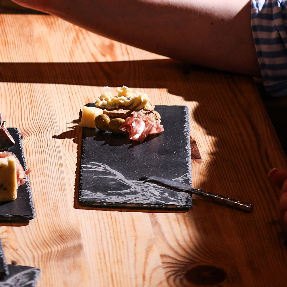 Served food on a slate board with a knife on a wooden table