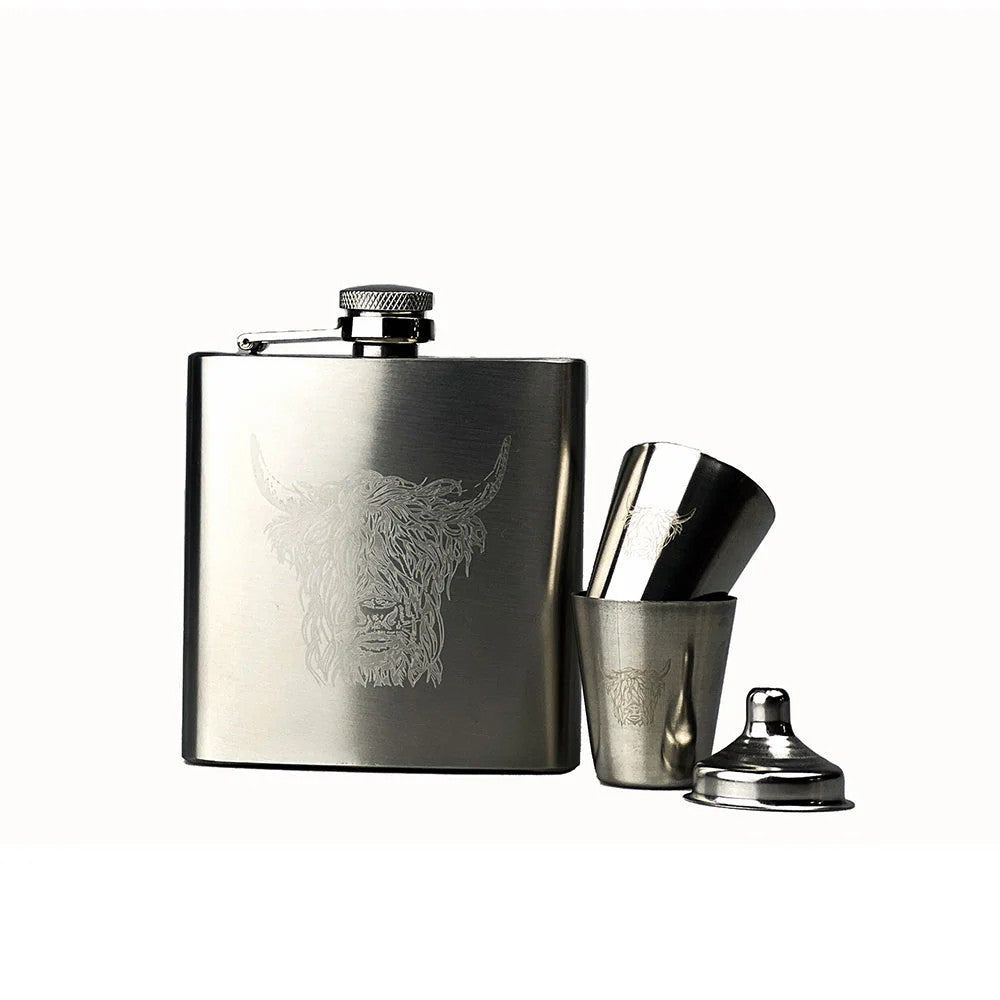 Stainless steel hip flask with engraved highland cow design, accompanied by a shot glass and jigger on a white background.