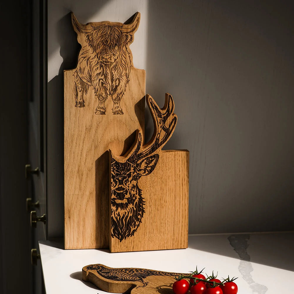 Wooden cutting board with engraved animal designs on a dark surface.
