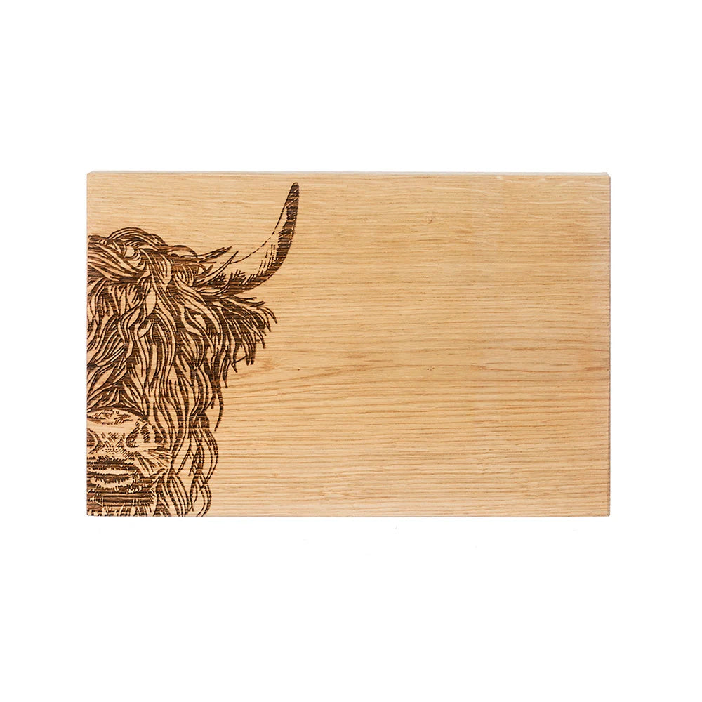 Wooden cutting board with a highland cow engraving on a white background
