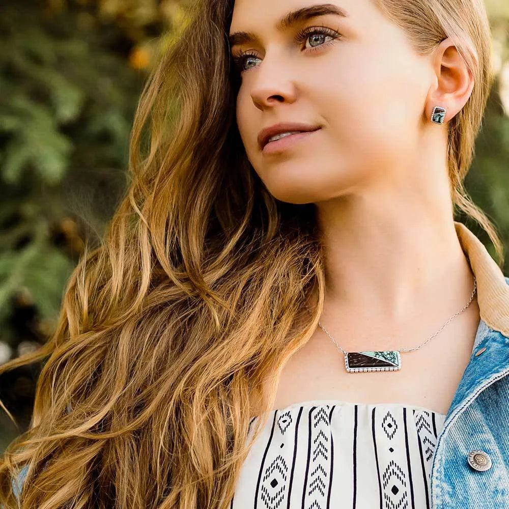 Woman wearing a necklace and earrings with a blurred natural background
