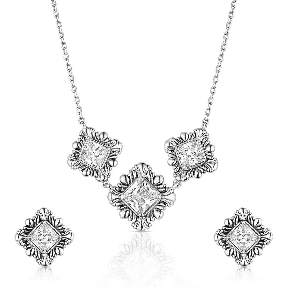 Silver necklace and earrings set with diamond-like stones on a white background