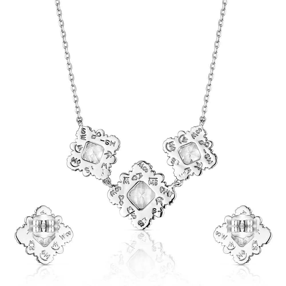 Silver necklace and earrings set with clear gemstones on a white background