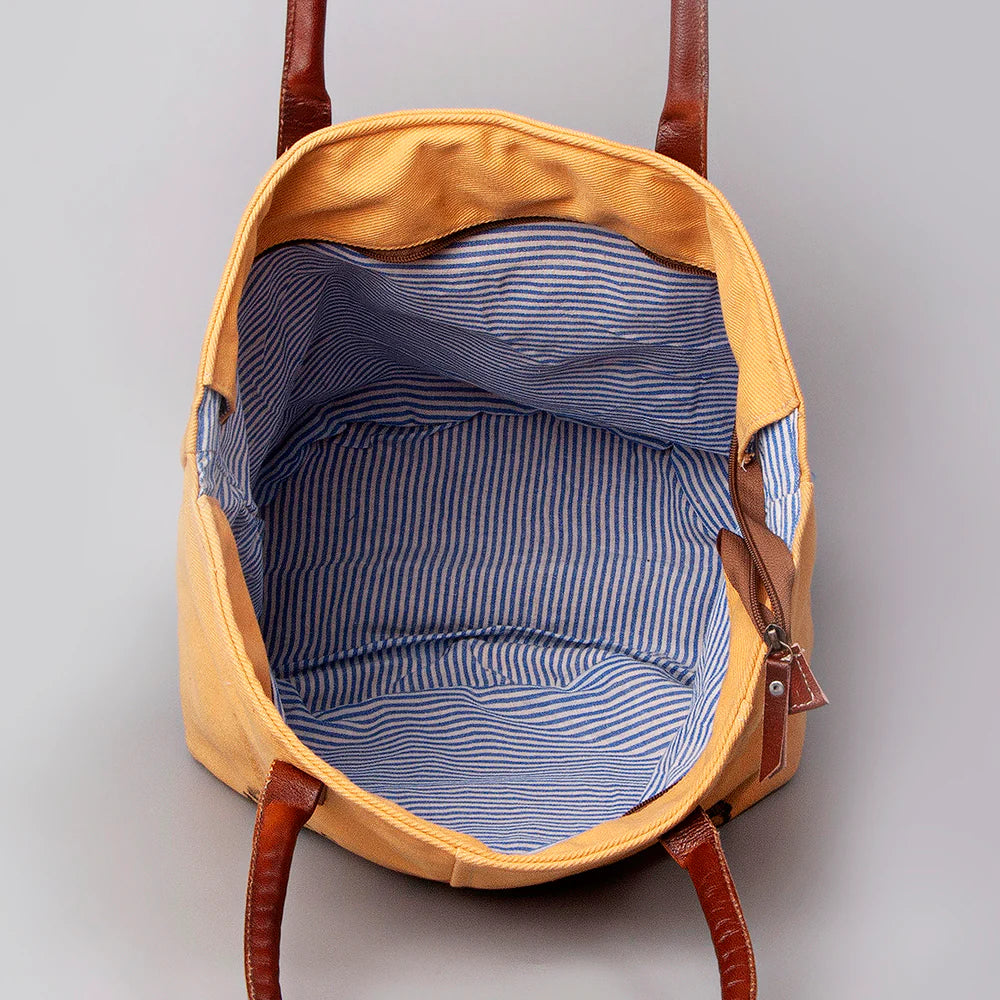 American Darling Upcylced Canvas Weekender Bag. Yellow backpack with brown straps on a gray background