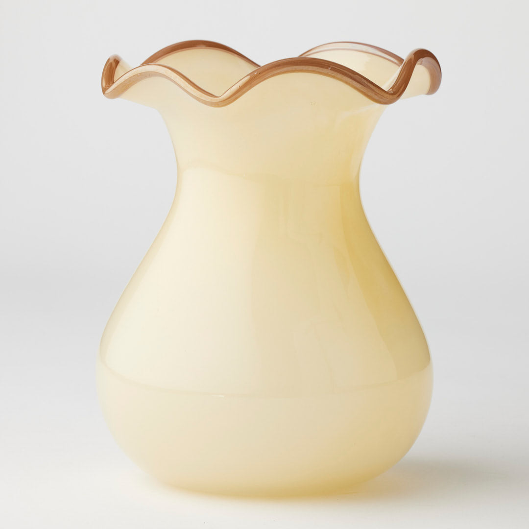Yellow glass vase with wavy rim on a light gray background
