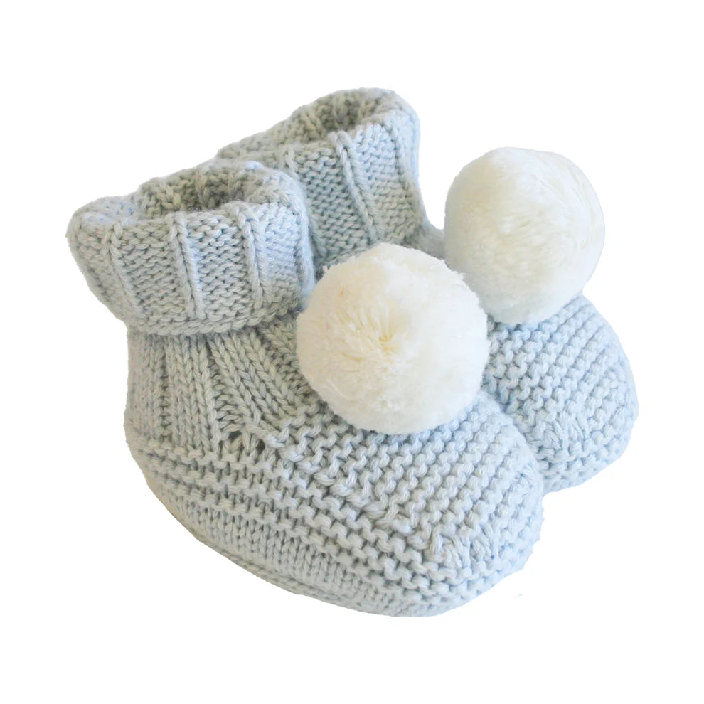 Knitted baby booties with white pom-poms on a white background