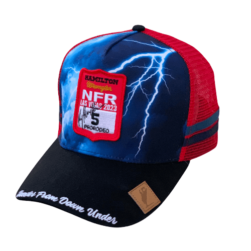 Ky Hamilton NFR Number Cap. A snapback cap with a blue and red design, featuring a patch with 'Hamilton NFR' and the year, as well as a photo of an individual under a sublimated design on the brim.