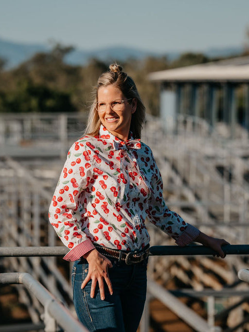 Kitty Fordè Emma Printed L/S Shirt. Woman standing in a livestock pen with mountains in the background