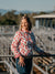 Kitty Fordè Emma Printed L/S Shirt. Woman standing in a livestock pen with mountains in the background
