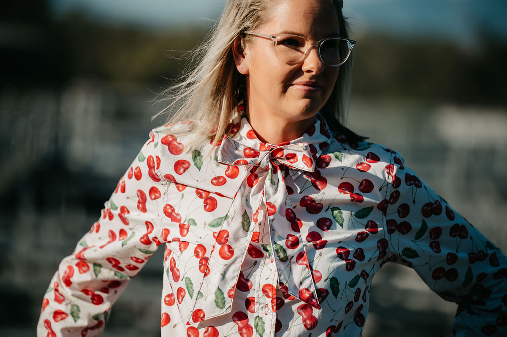 Kitty Fordè Emma Printed L/S Shirt. Woman wearing a blouse with red cherry pattern outdoors