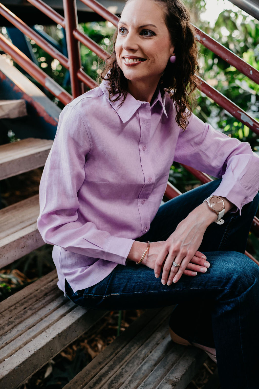 Kitty Fordè Grace Plain Linen L/S Shirt. Woman wearing a light purple shirt sitting on wooden steps outdoors