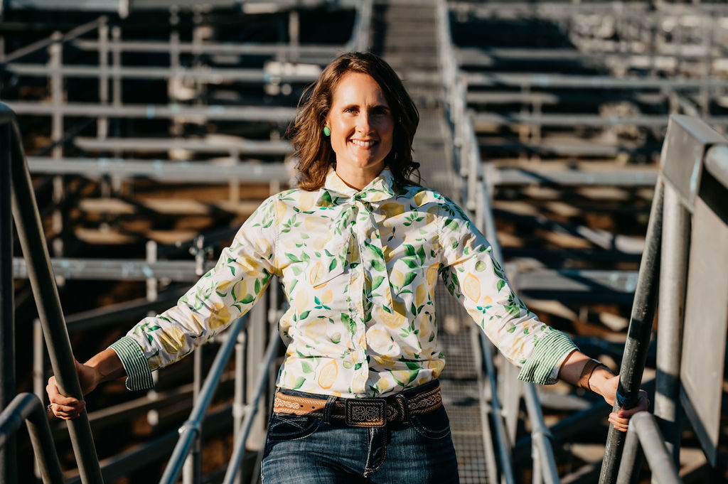 Woman standing in a livestock pen wearing a patterned shirt