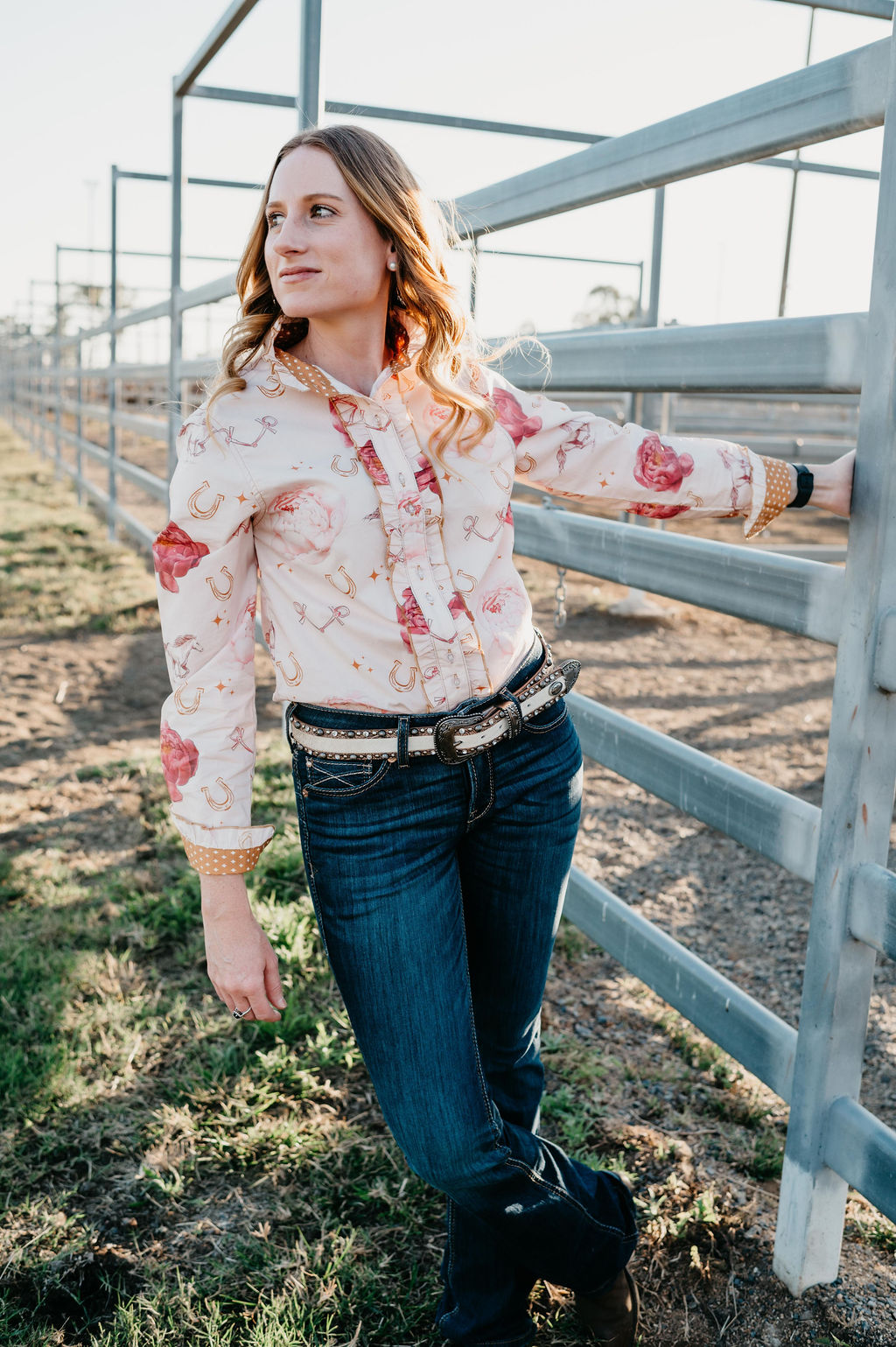 Kitty Fordè Lisa Printed L/S Shirt Woman in a floral shirt and jeans standing next to a metal fence outdoors.