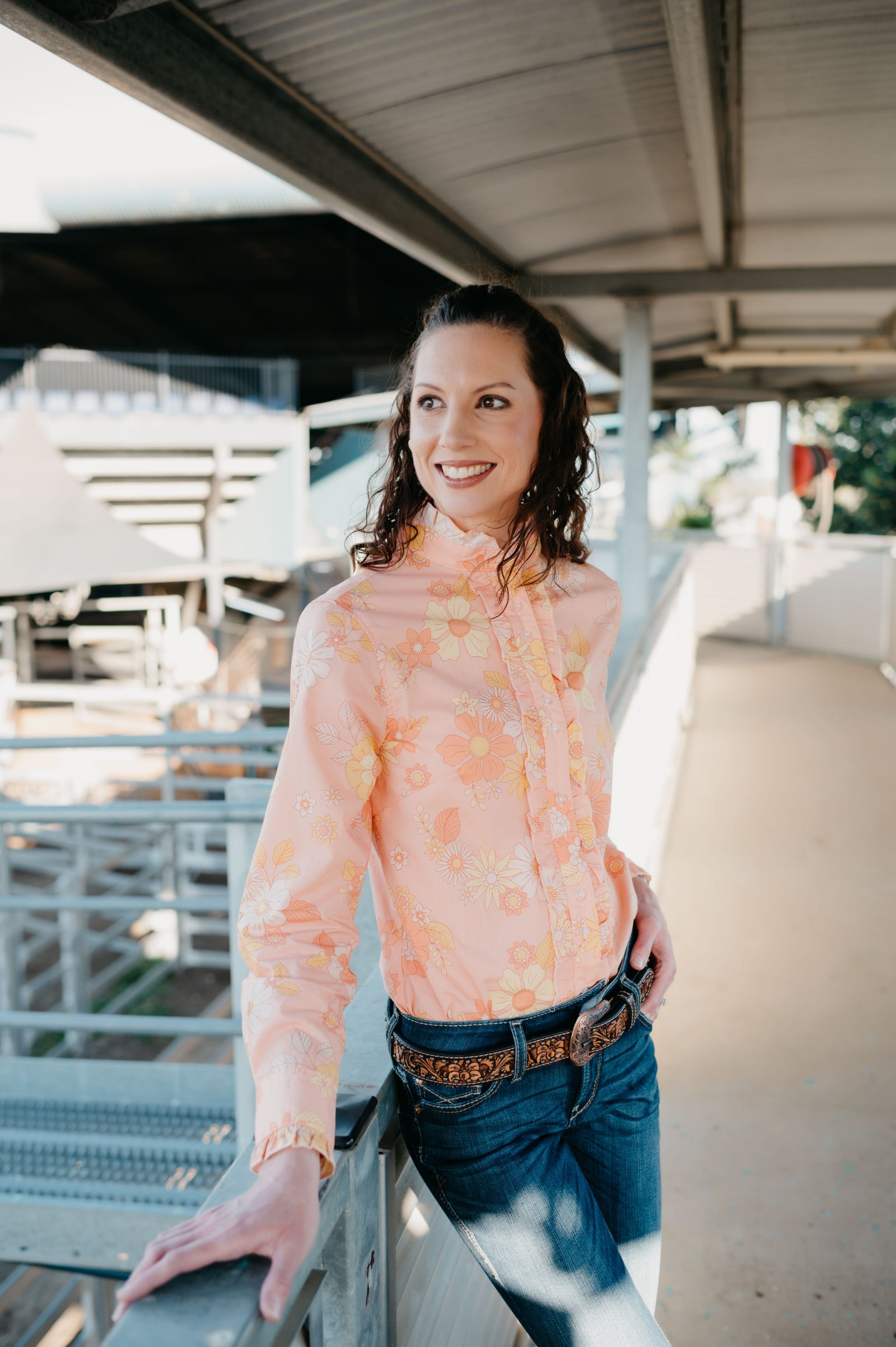 Woman wearing a floral blouse and jeans standing on a bridge