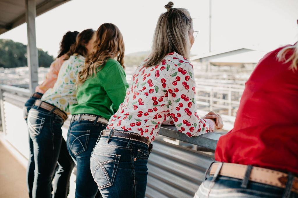 Group of women standing together, possibly at a race track, wearing casual outfits.