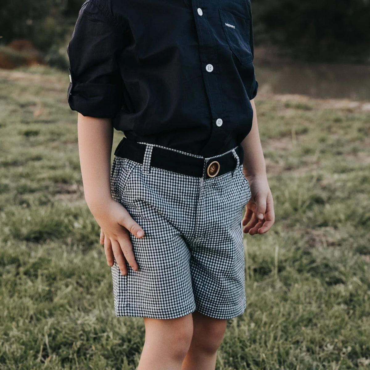 Love Henry Boy's Oscar Shorts. Navy gingham checkered shorts with a functional button fastening at the front and a decorative button on the right back pocket, featuring an elasticated waistband.