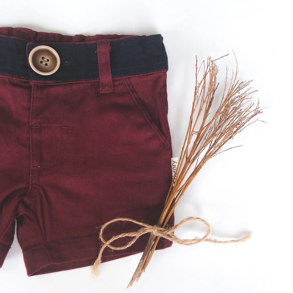 Love Henry Infant Boy's Oscar Shorts. A pair of maroon infant boy's shorts with a belt, button fastening, and pockets, accompanied by a pair of brown shoes.