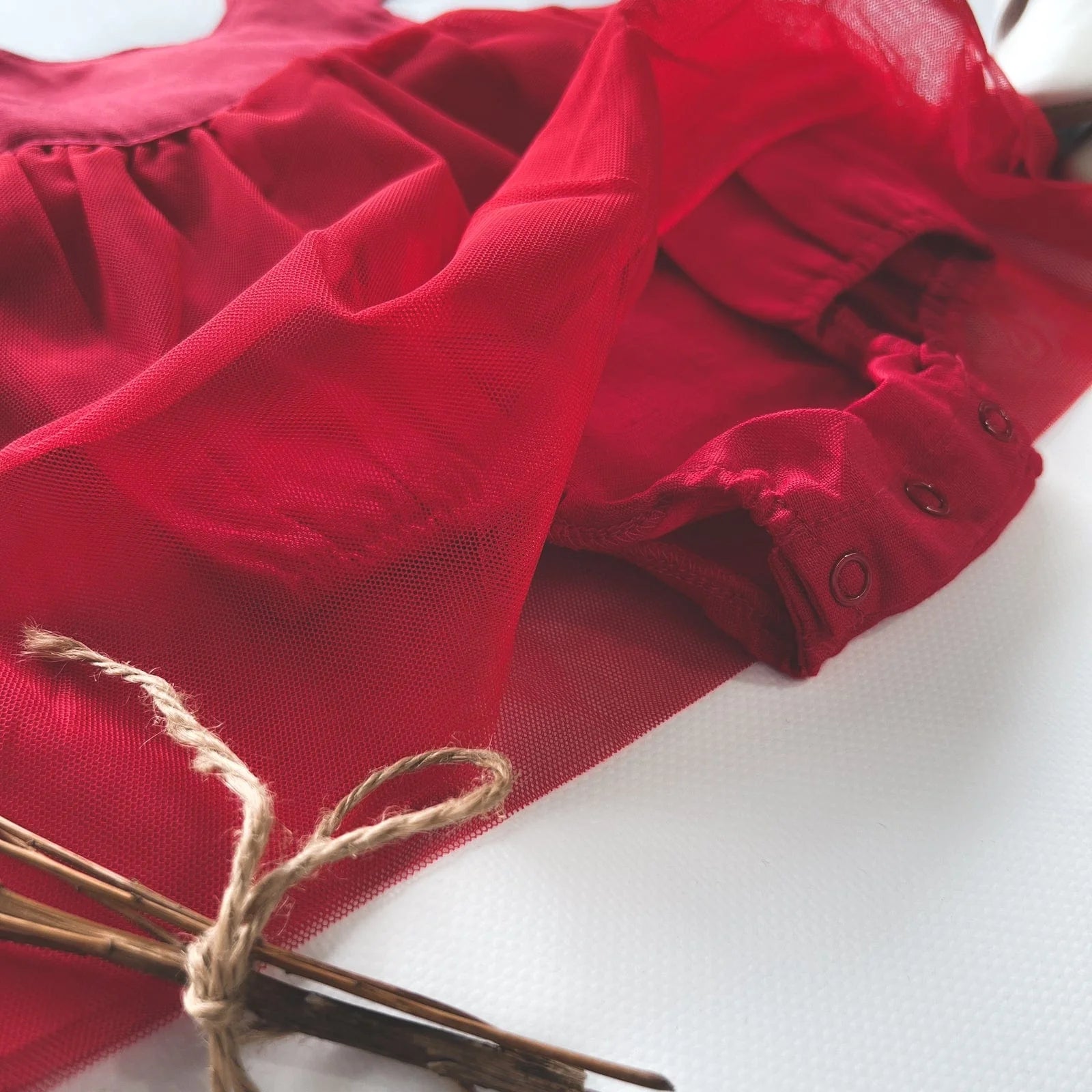 Love Henry Infant Girl's Lottie Dress. A red infant girl's dress with a pleated waist and sleeveless design, accompanied by a pair of shoes and a small decorative bow.