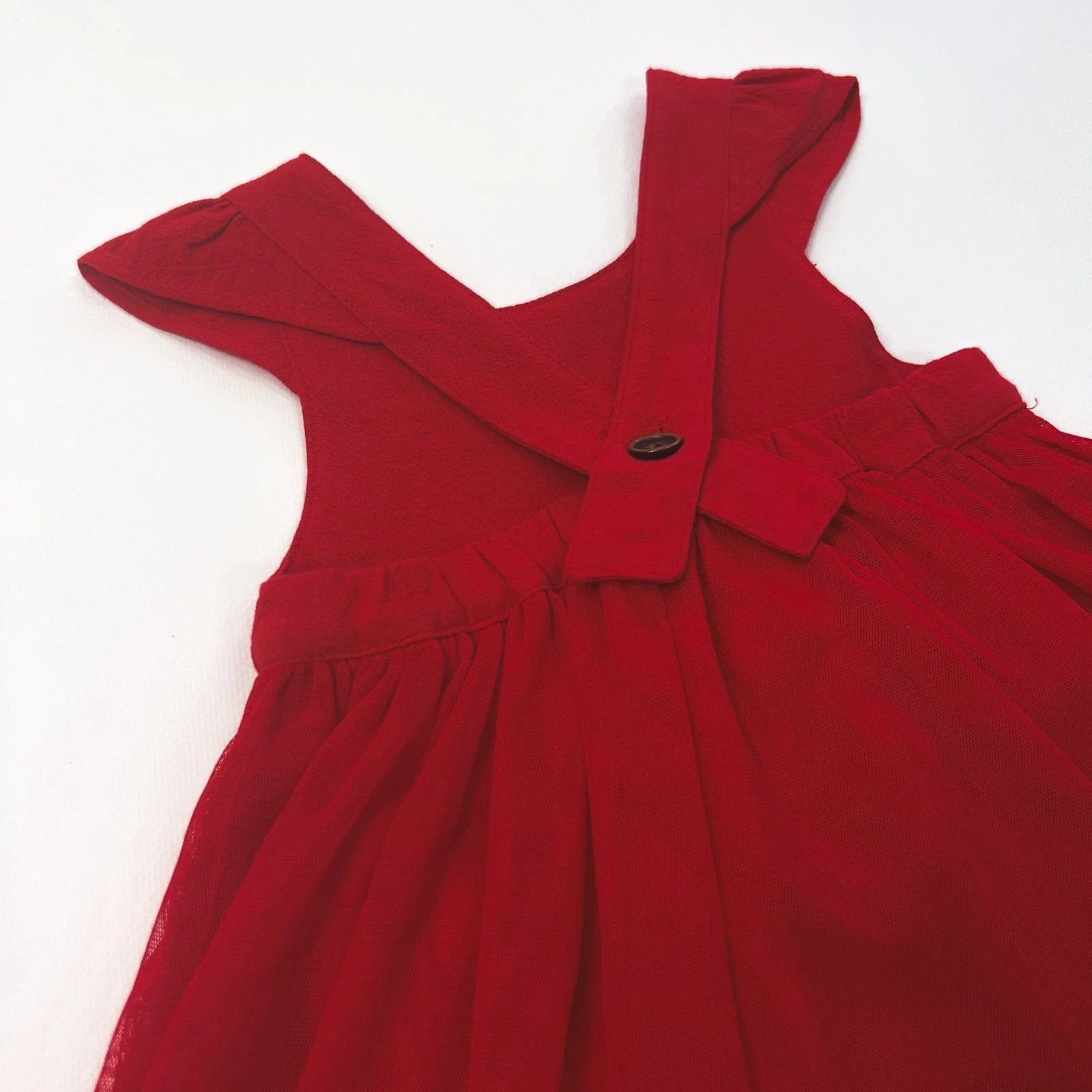 Love Henry Infant Girl's Lottie Dress. A red infant girl's dress with a pleated waist and sleeveless design, accompanied by a pair of shoes and a small decorative bow.