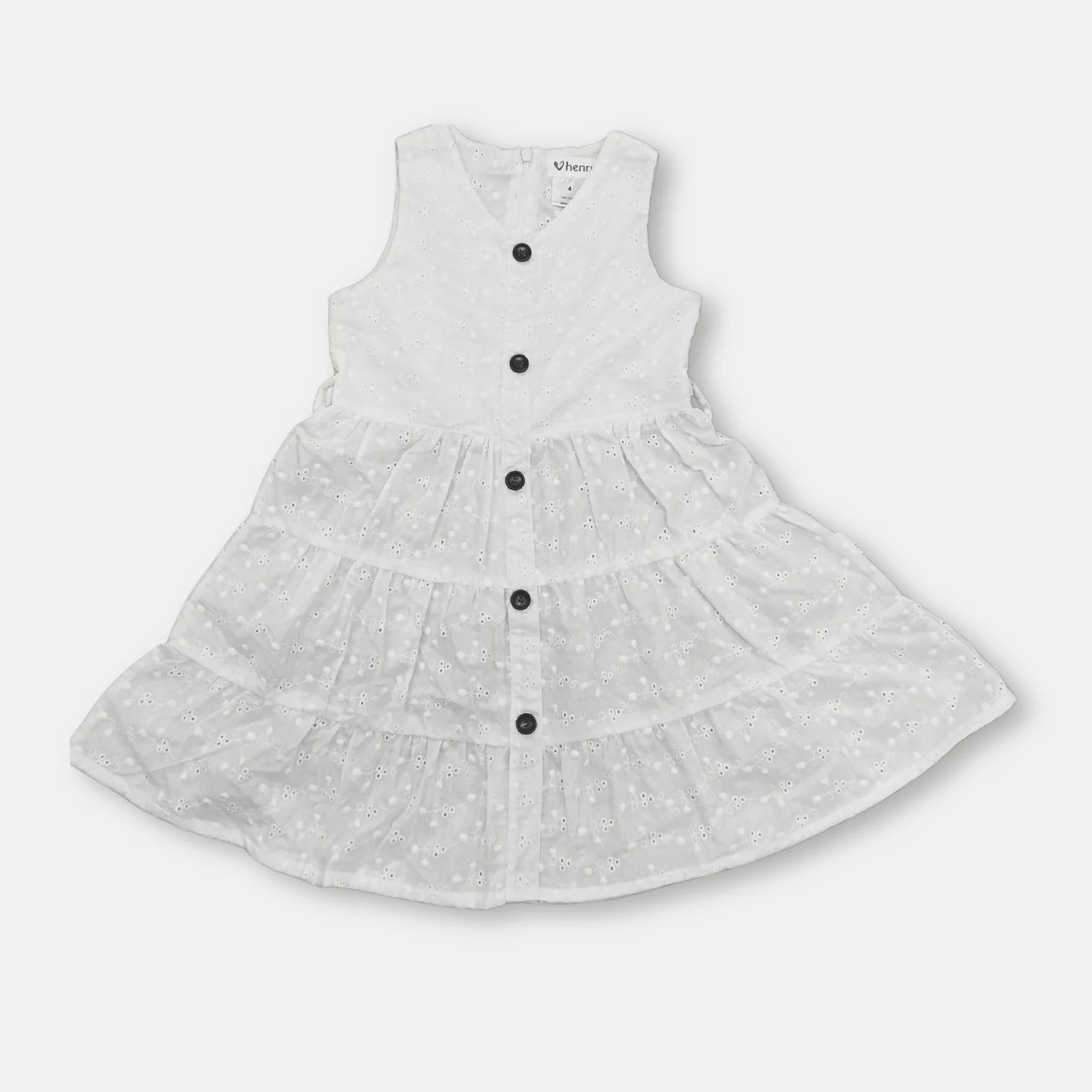Love Henry Girl's Alice Dress. A young girl wearing a white sleeveless knee-length dress with buttons down the front, standing in a field.