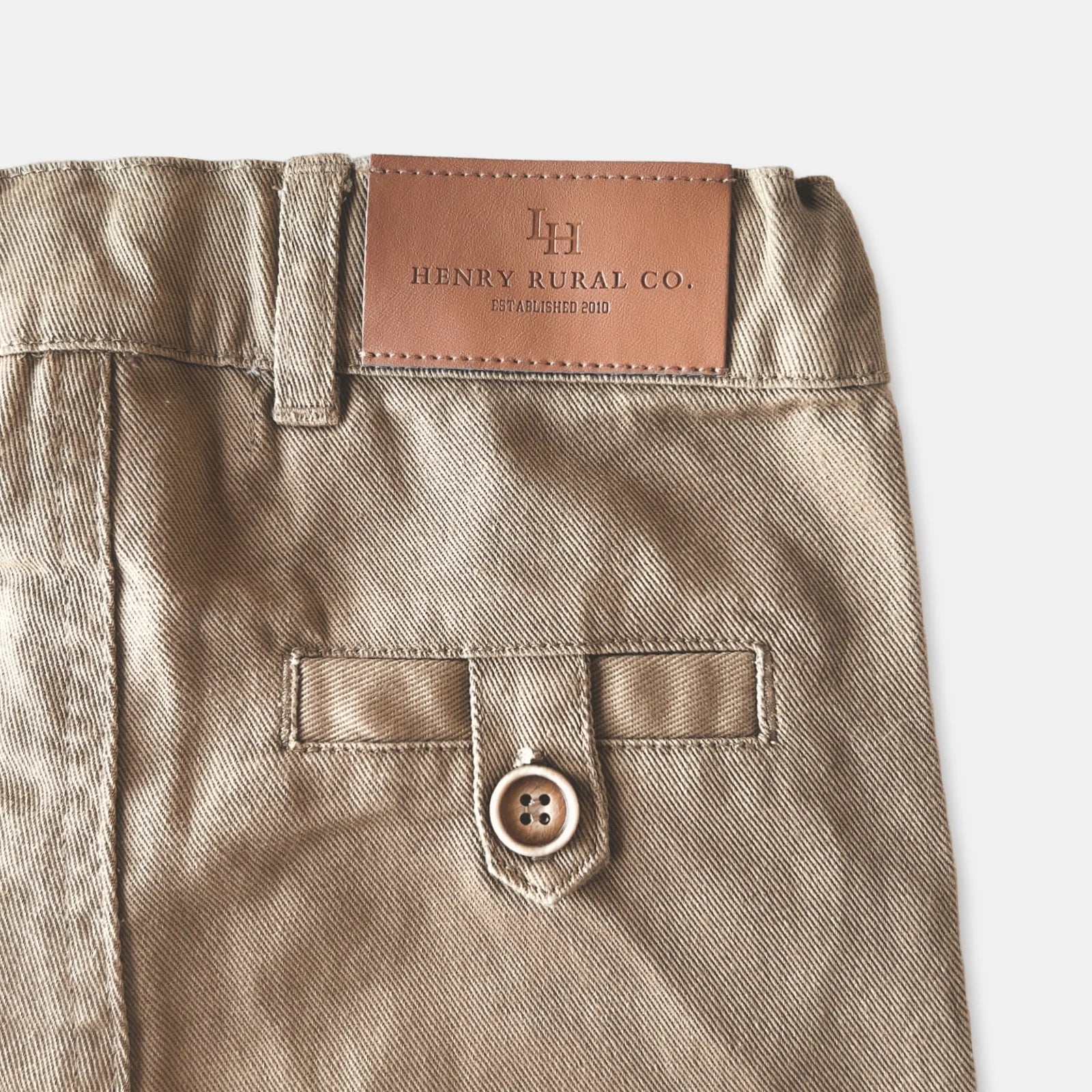 Love Henry Boy's Chino Pants. A pair of brown chino pants for boys laid flat on a white background.