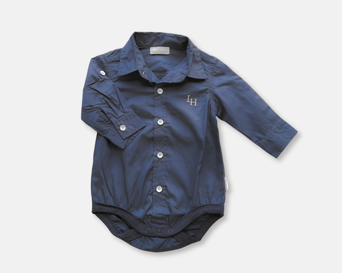 Love Henry Baby Boy&#39;s Dress Shirt Romper. A navy blue long-sleeve baby boy&#39;s dress shirt romper with button-down closure, buttoned cuffs, and a small embroidered logo on the chest. It also features a breast pocket and press-stud fastening.