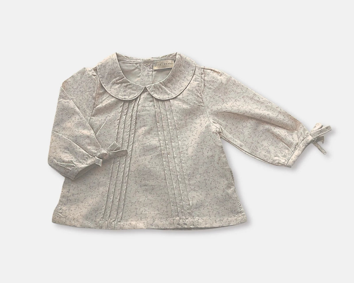 Love Henry Baby Girl&#39;s Shirt Top. A beige long-sleeved baby girl&#39;s blouse with a Peter Pan collar and embellishments on the chest.