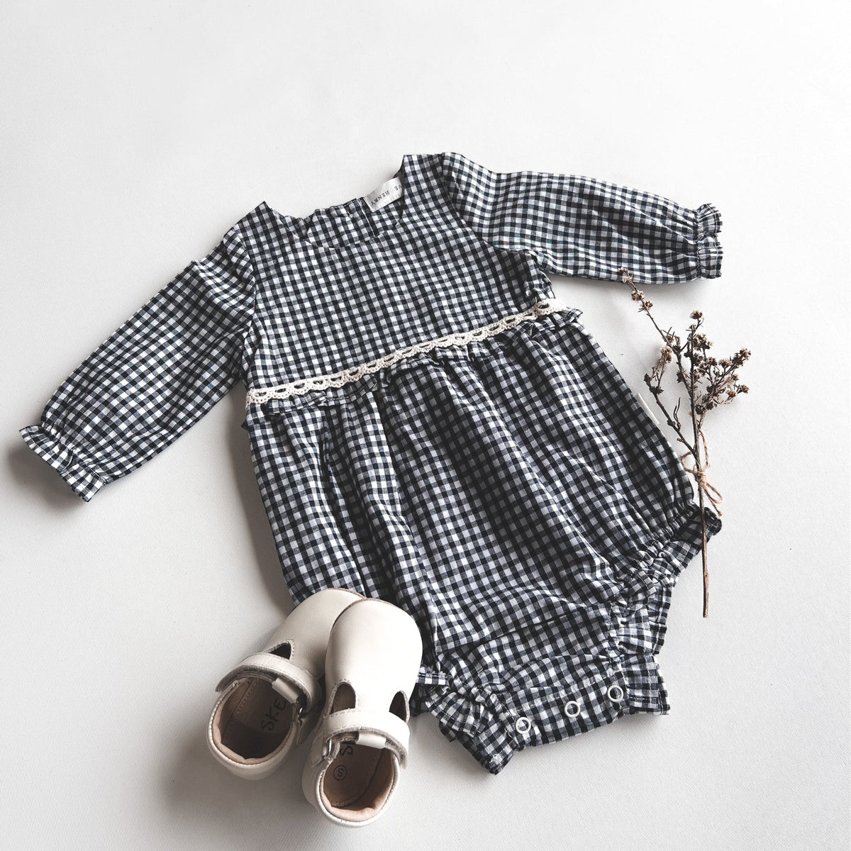 Love Henry Baby Girls L/S Nora Playsuit - Navy Check. Navy and white checkered baby romper with white shoes on a light gray background