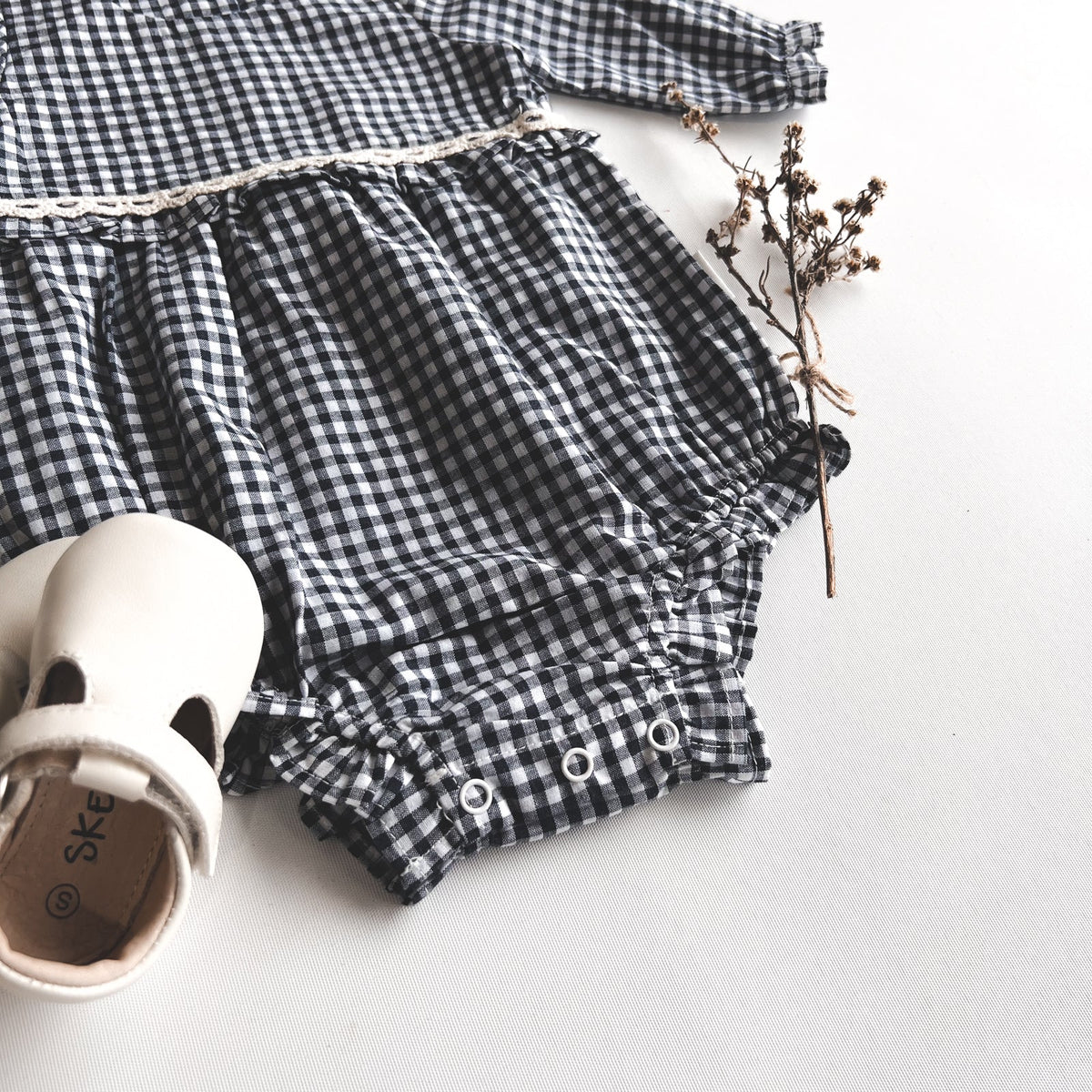 Love Henry Baby Girls L/S Nora Playsuit - Navy Check. Navy and white checkered romper with ruffled details on a light background