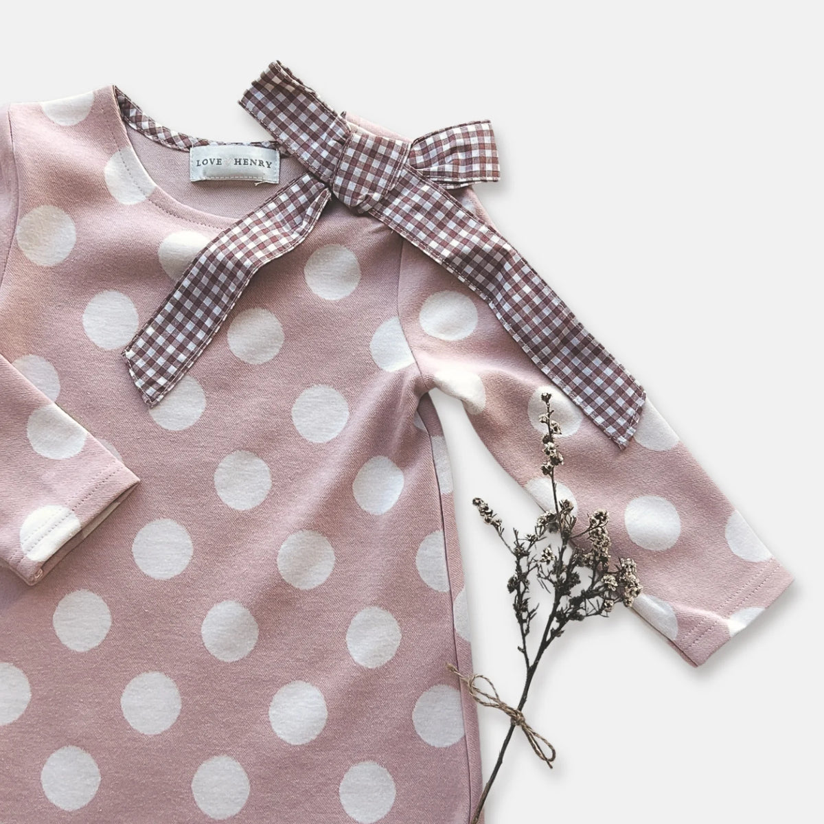 Love Henry Girl's Mary Dress. Pink polka dot dress with checkered bow on a white background