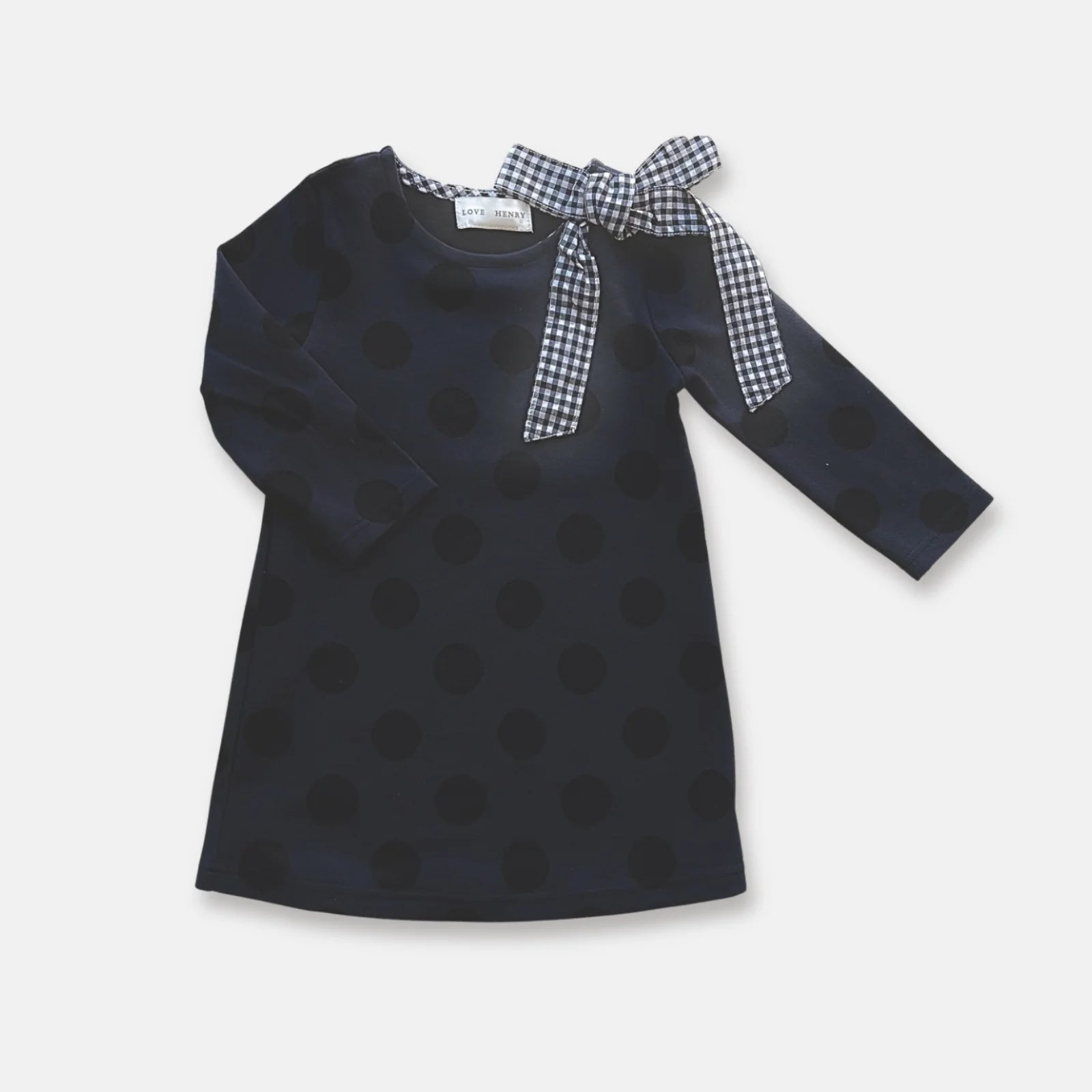 Love Henry Girl's Mary Dress. Navy polka dot dress with checkered bow on plain background