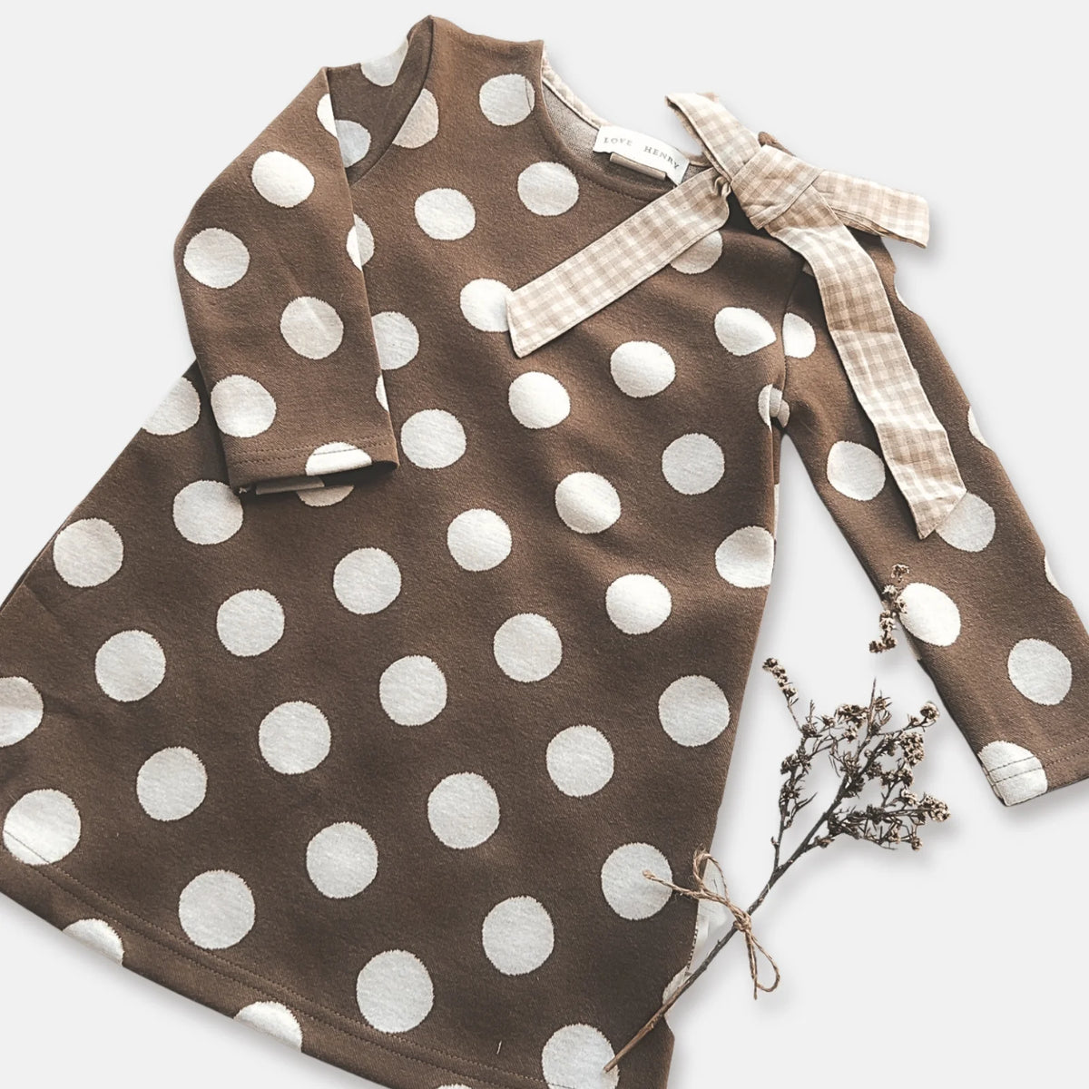 Love Henry Girl's Mary Dress. Brown dress with white polka dots and bow on a white background