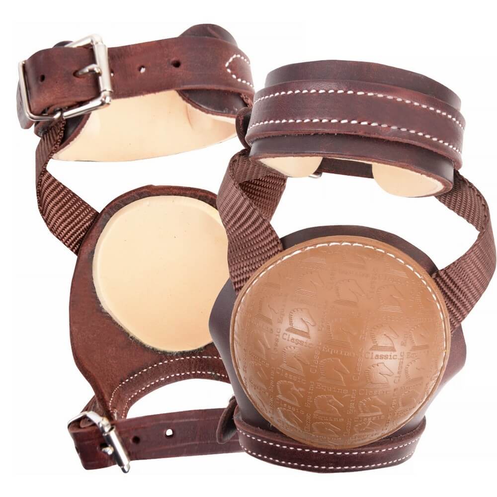 Classic Equine Leather Skid Boot. A set of brown leather horse skid boots with stainless steel buckles and a beige-colored skid cup.
