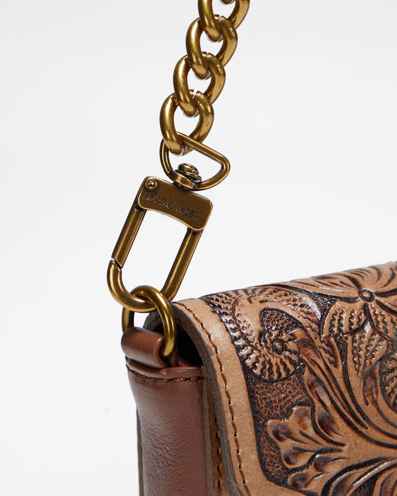 Loyal West The On The Go Mini Chain Bag. Close-up of a brown leather handbag with intricate tooled design and gold chain strap.