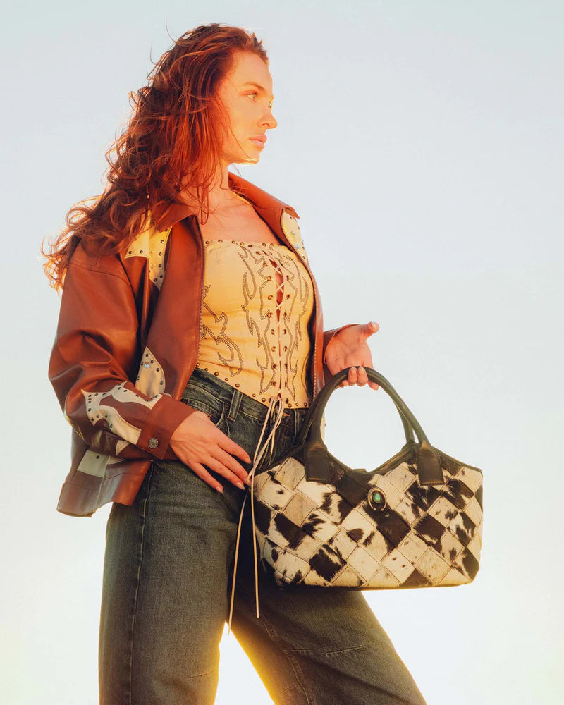 Woman holding a patterned handbag against a light background