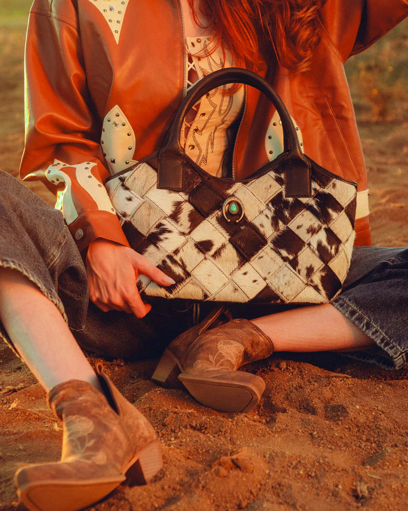 Person holding a patterned handbag with a rustic background