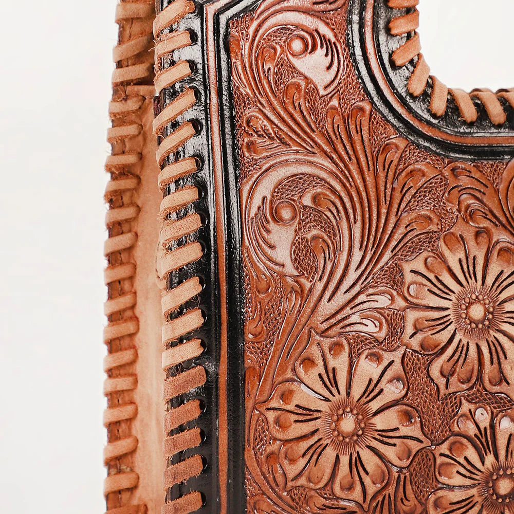 Loyal West Alma Medium Western Handbag. Close-up of a leather-bound book with intricate floral tooled design on a white background
