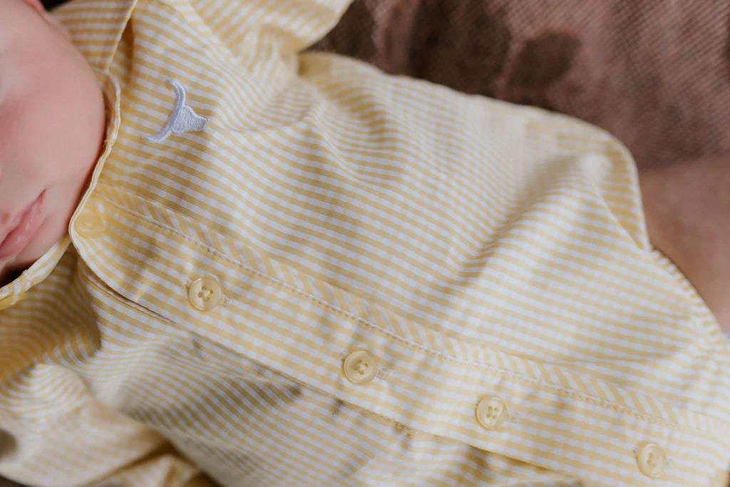 Close-up of a baby wearing a yellow striped outfit with buttons.